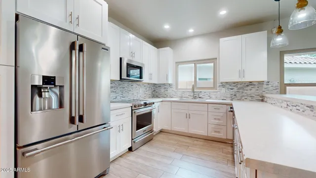 a kitchen with granite countertop a refrigerator stove and sink
