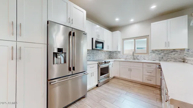 a kitchen with granite countertop a refrigerator stove and sink