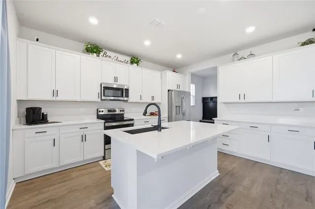 a kitchen with white cabinets appliances and sink