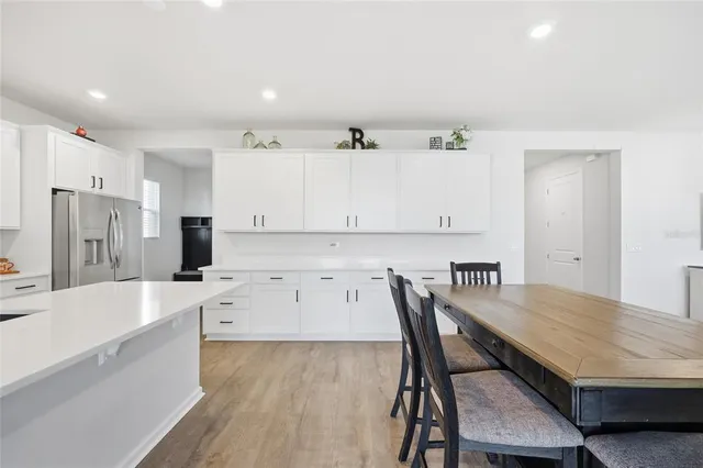 a kitchen with stainless steel appliances granite countertop a table chairs and a refrigerator