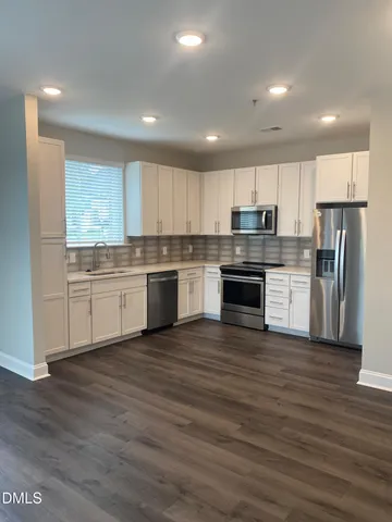 a kitchen with stainless steel appliances granite countertop a stove top oven a sink and white cabinets