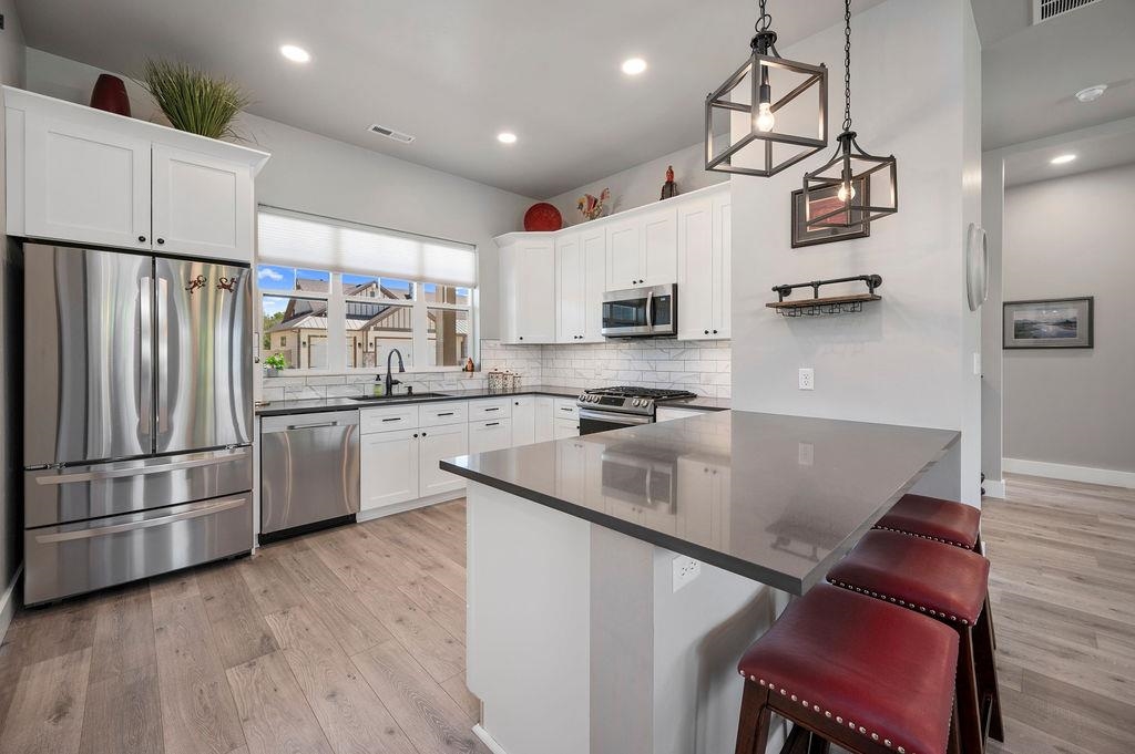 813 Red Apple Road Grand Junction, CO 81505 - Photo 15 of 30 a kitchen with stainless steel appliances granite countertop a sink a stove a refrigerator cabinets and a chairs with wooden floor