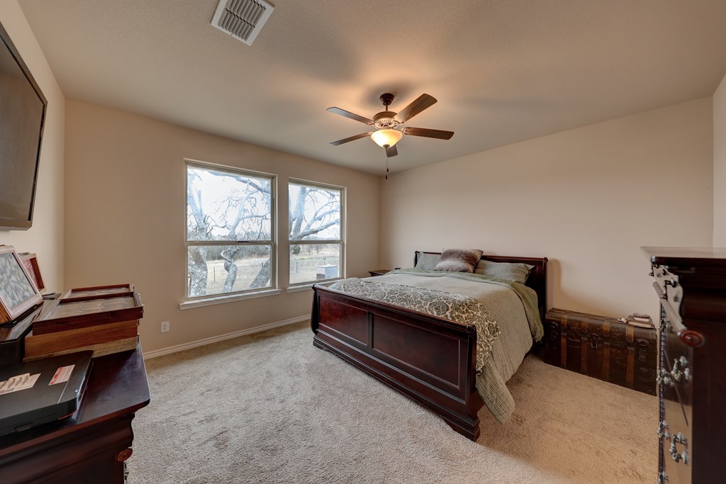 450 Jung Road Harper, TX 78631 - Photo 14 of 50 a spacious bedroom with a bed and a chandelier
