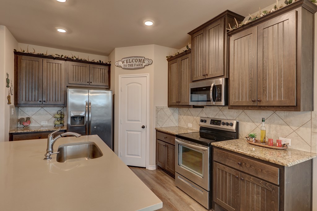 450 Jung Road Harper, TX 78631 - Photo 10 of 50 a kitchen with stainless steel appliances granite countertop a sink a stove and a refrigerator