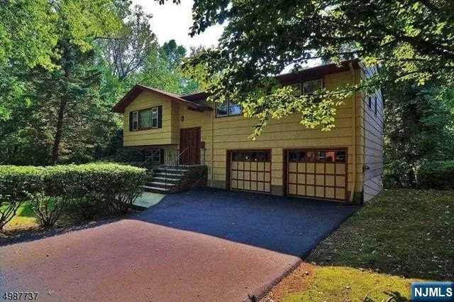 a view of a house with brick walls plants and large tree