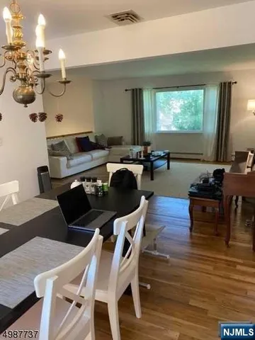 a view of a dining room with furniture a chandelier and wooden floor