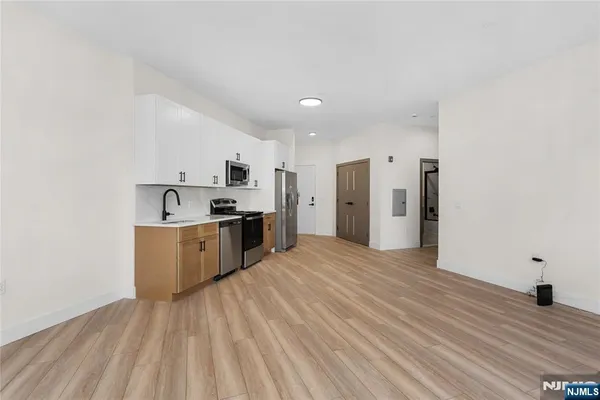 a view of kitchen with stainless steel appliances granite countertop a stove a sink dishwasher and a refrigerator with wooden floor