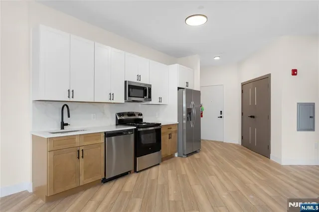 a kitchen with a sink a refrigerator and cabinets