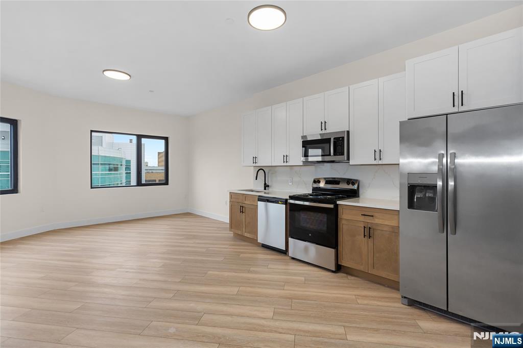 89 Mary Street, Unit 505 Paterson, NJ 07503 - Photo 9 of 10 a kitchen with stainless steel appliances granite countertop a stove a sink and a refrigerator