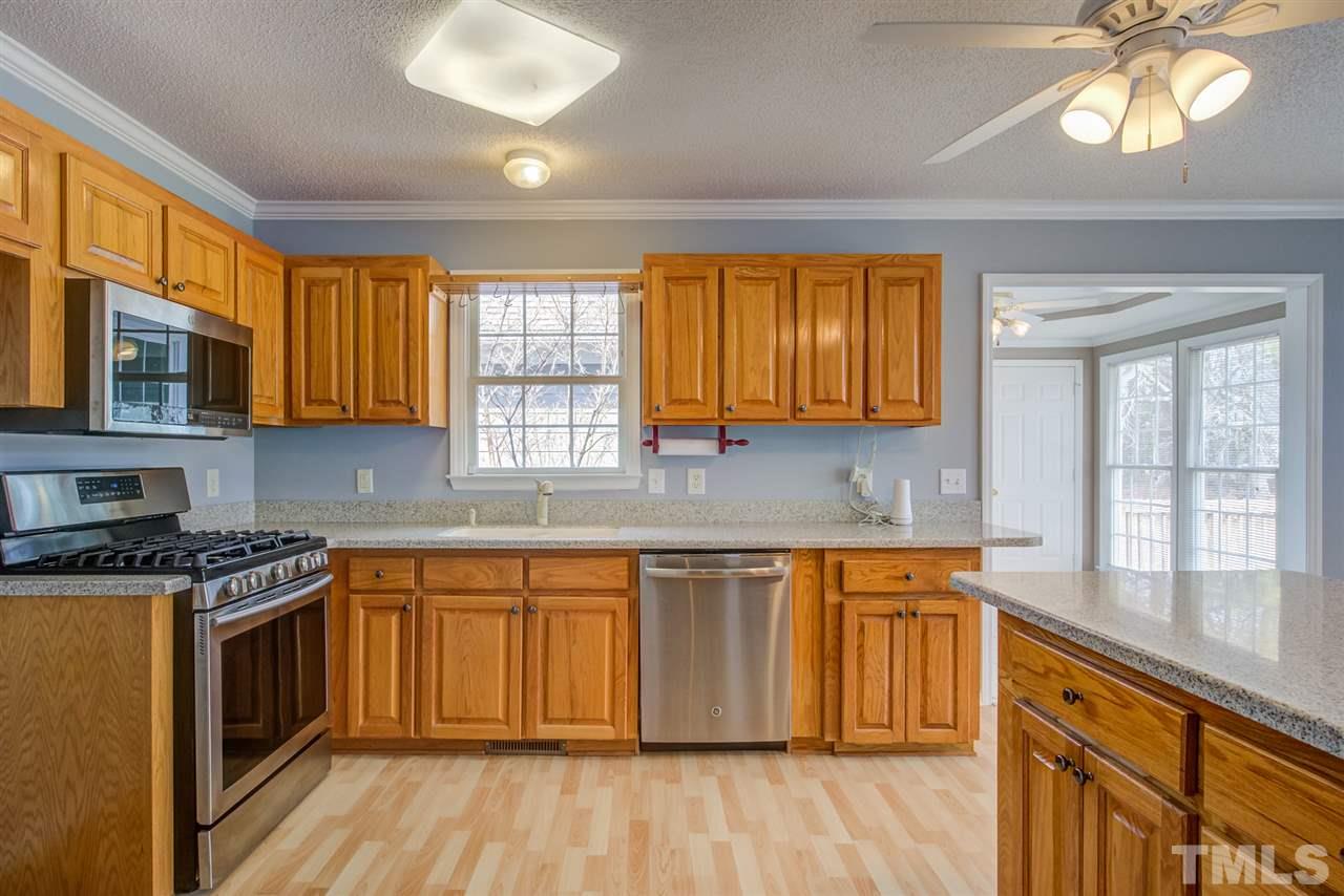 1020 Transom Court Raleigh, NC 27603 - Photo 11 of 30 a kitchen with stainless steel appliances wooden floors and wooden cabinets
