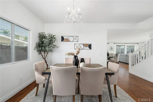 a kitchen with stainless steel appliances kitchen island granite countertop a stove a sink dishwasher a refrigerator and white cabinets with wooden floor