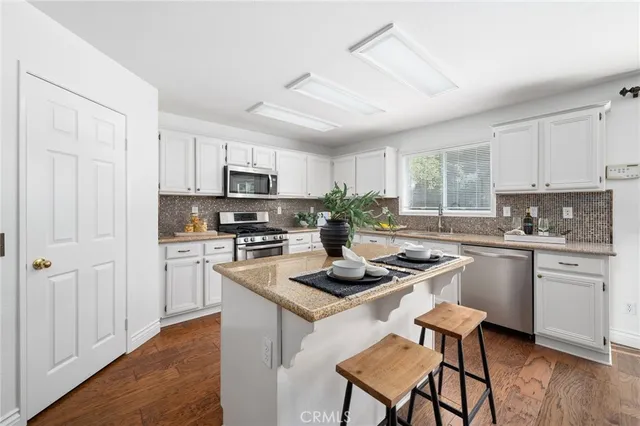 a kitchen with kitchen island granite countertop a sink a counter top space appliances and cabinets