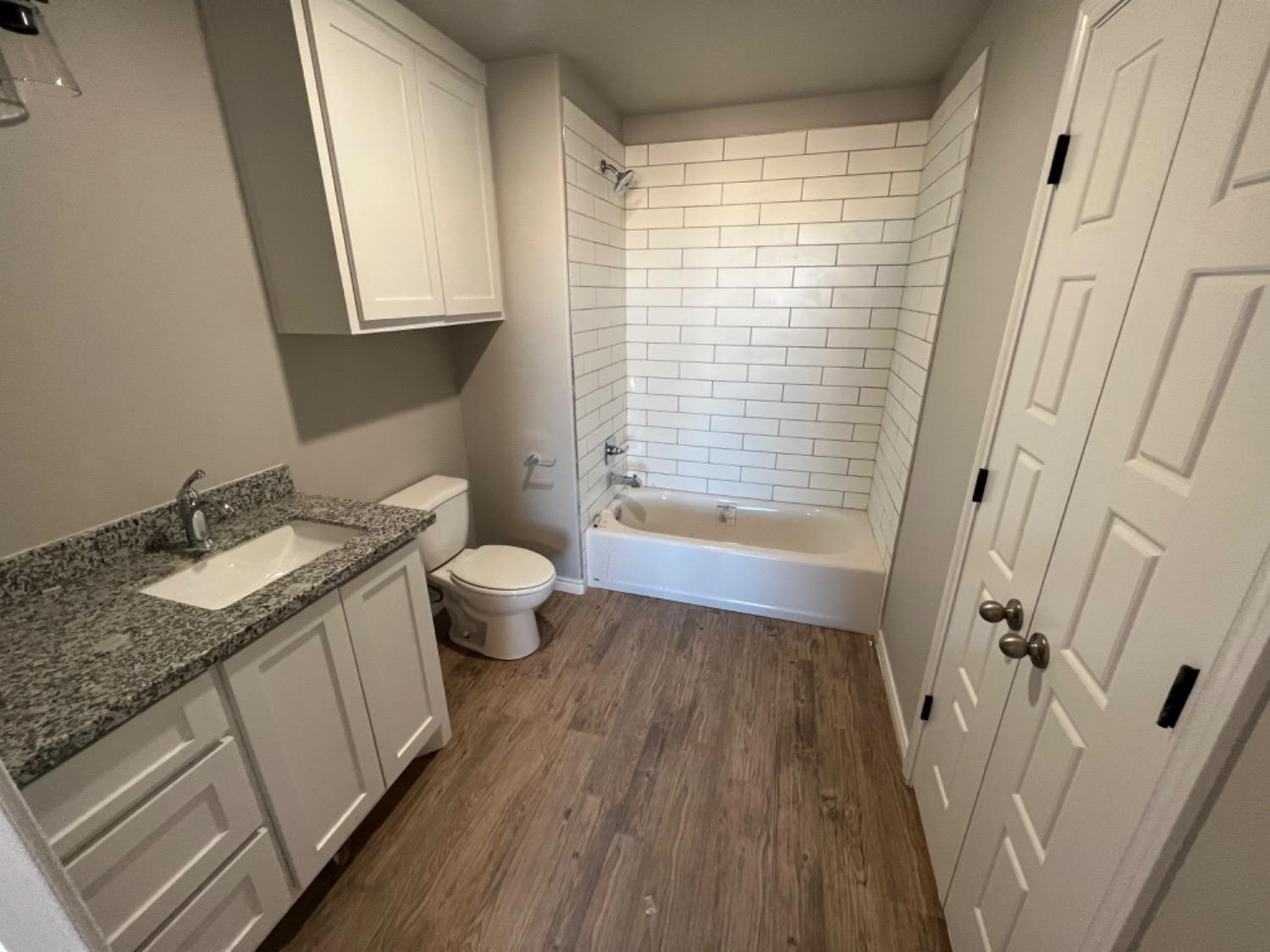 1407 17th Street, Unit AB Shallowater, TX 79363 - Photo 23 of 33 a bathroom with a granite countertop sink toilet and shower