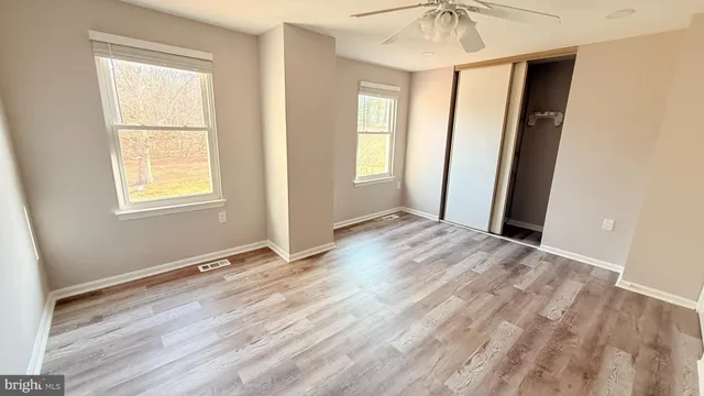 an empty room with window and hardwood floor
