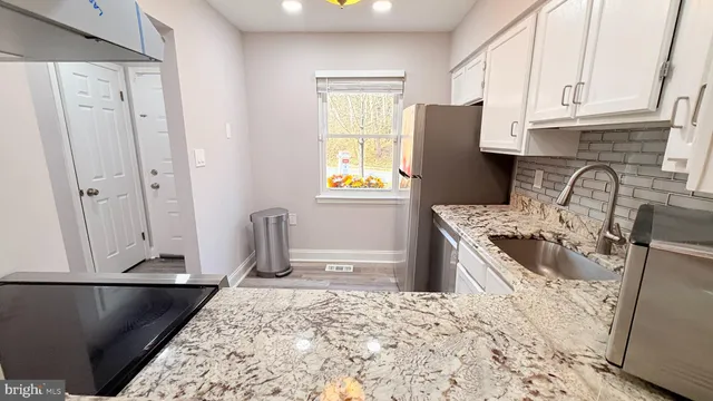 a kitchen with granite countertop a refrigerator stove and sink