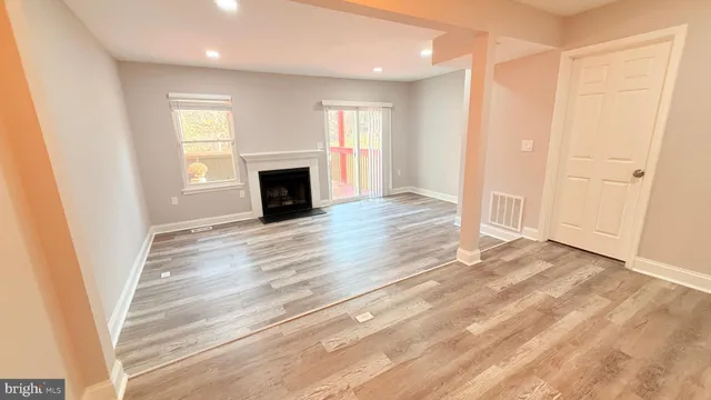 an empty room with wooden floor fireplace and windows