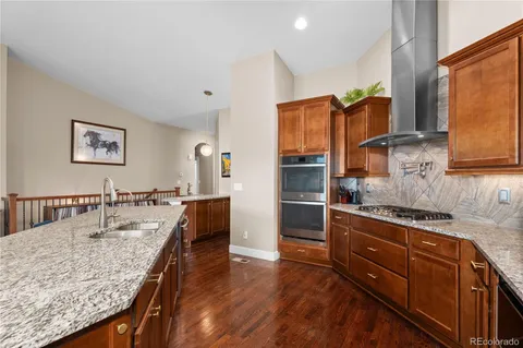 a kitchen with stainless steel appliances granite countertop a sink dishwasher stove and refrigerator with wooden floor