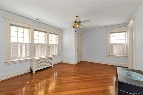 a view of an empty room with a window and wooden floor