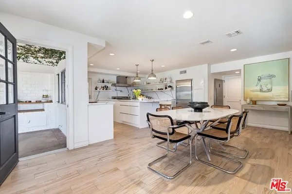 a dining hall with stainless steel appliances kitchen island granite countertop a dining table chairs and view living room