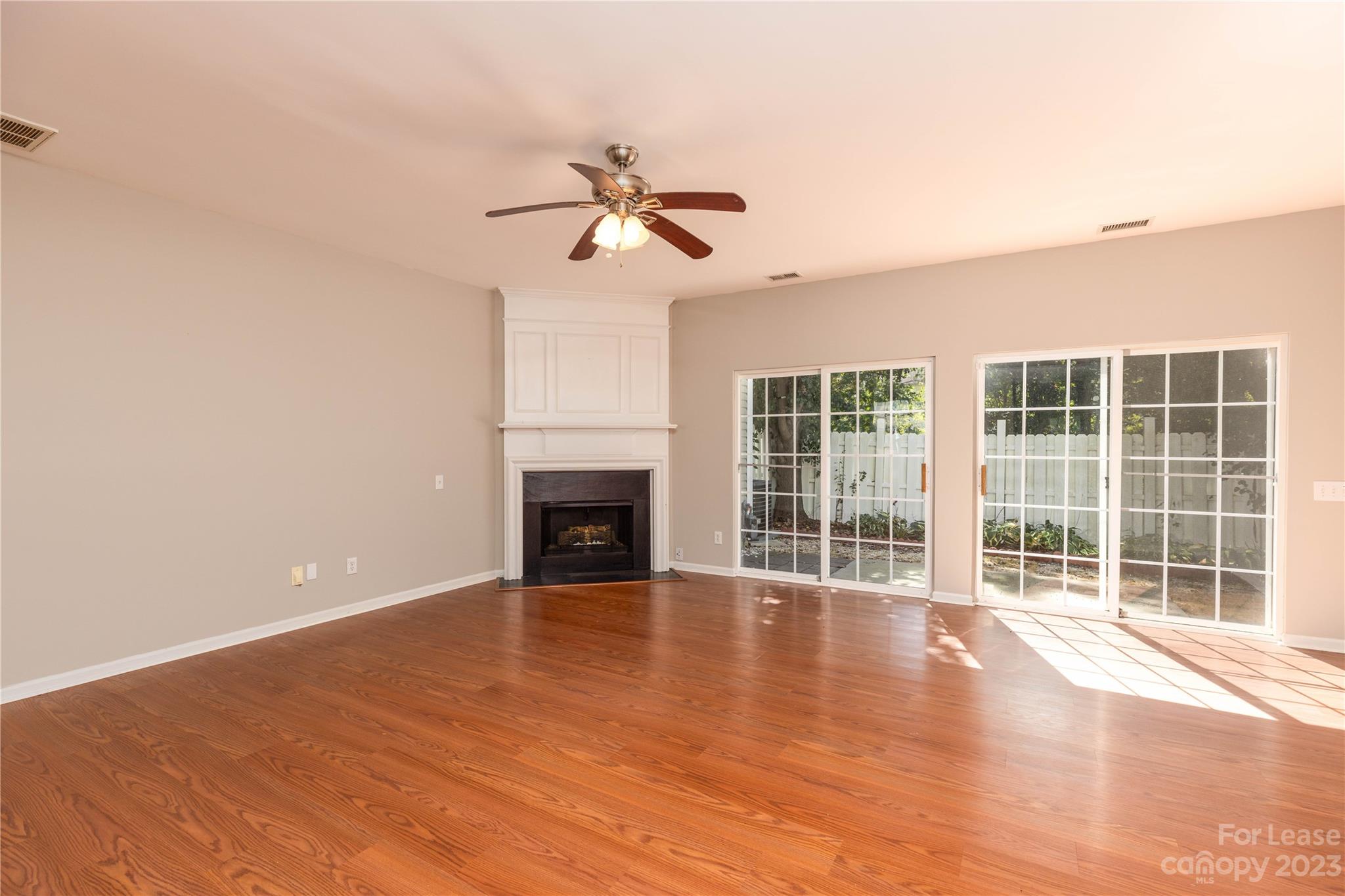 6879 Rothchild Drive Charlotte, NC 28270 - Photo 6 of 19 an empty room with windows fireplace and a ceiling fan