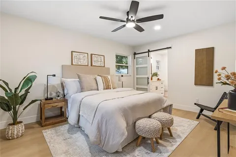 a bedroom with a bed a chair and potted plant on the dresser