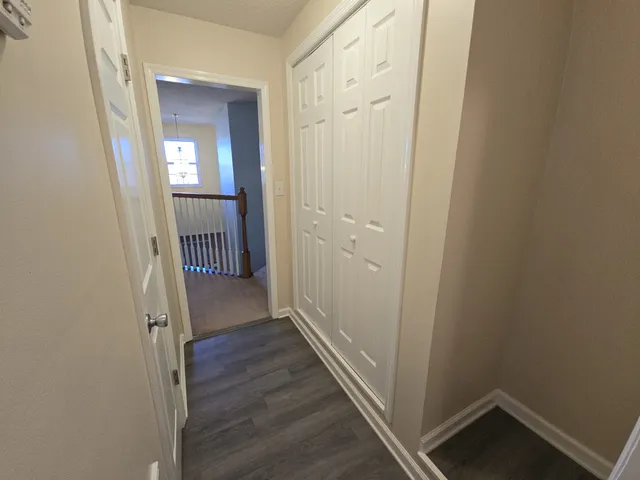 a view of a hallway with wooden floor and a bathroom