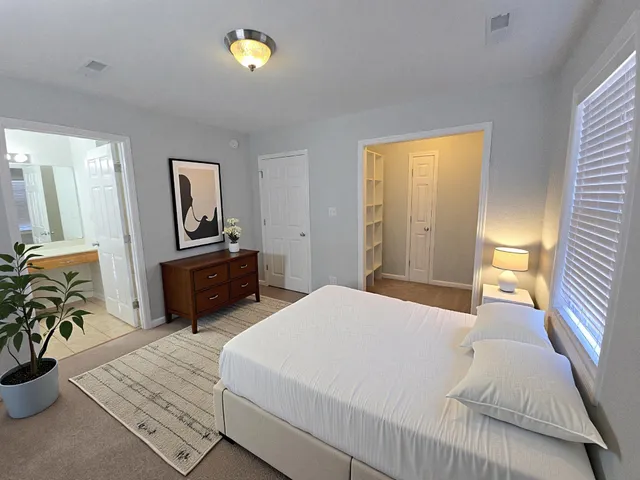 a bedroom with a bed a potted plant on dresser and a wooden floor