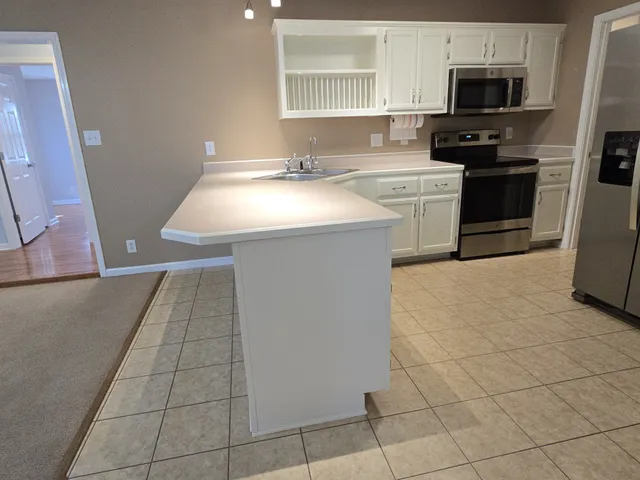 a kitchen with a sink a stove top oven and cabinetry