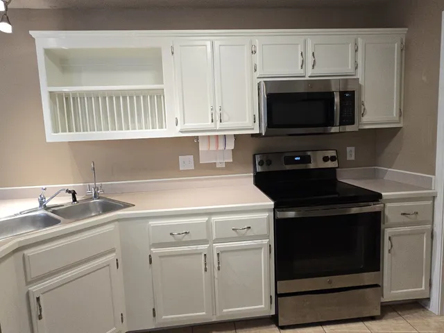 a kitchen with white cabinets and black appliances