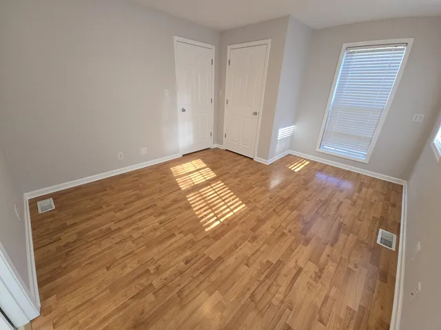 a view of empty room with wooden floor and fan