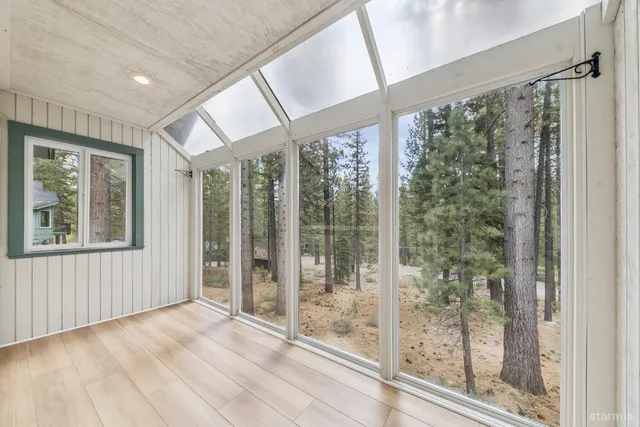 a view of an empty room with wooden floor and windows