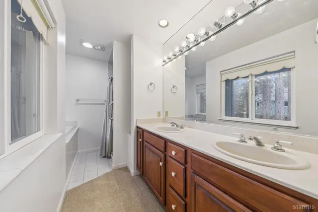 a bathroom with a sink double vanity granite tub and shower