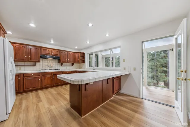 a kitchen with stainless steel appliances granite countertop a stove a sink dishwasher and a refrigerator with wooden cabinets