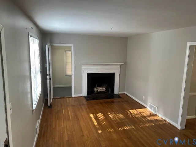 a view of empty room with wooden floor and fireplace