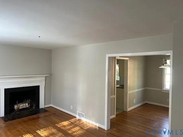a view of a livingroom with wooden floor a fireplace and window