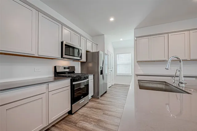 a kitchen with kitchen island granite countertop a sink stainless steel appliances and cabinets