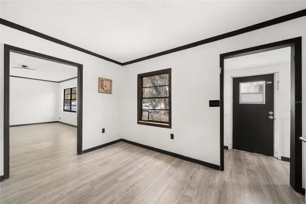 a view of an empty room with wooden floor and a window