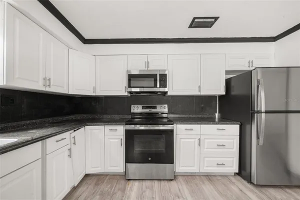 a kitchen with white cabinets and stainless steel appliances