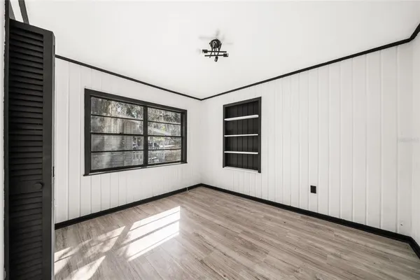 a view of an empty room with a window and wooden floor