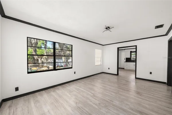 an empty room with wooden floor and windows