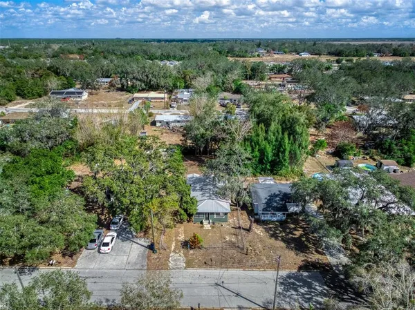an aerial view of residential houses with outdoor space and trees