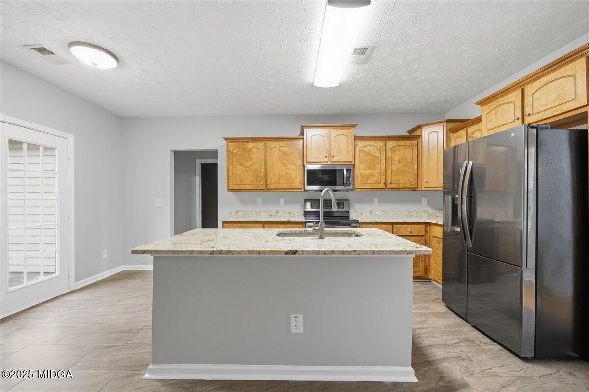 2764 Dames Ferry Road Forsyth, GA 31029 - Photo 8 of 30 a kitchen with stainless steel appliances granite countertop a sink a refrigerator and a granite counter tops