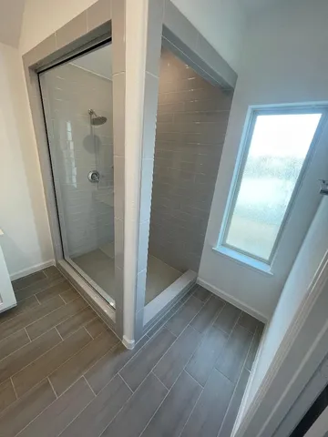 a bathroom with a glass shower door and a window