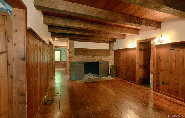 a view of an empty room with wooden floor and a fireplace