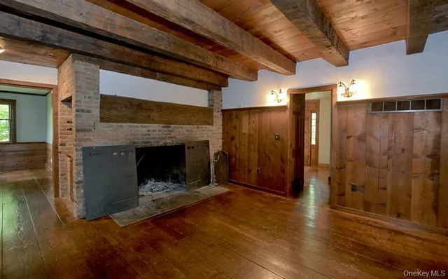 a view of an empty room with wooden floor fireplace and a window