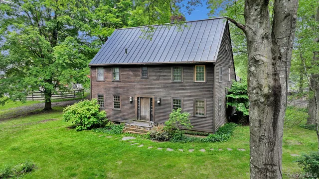 a backyard of a house with plants and large tree