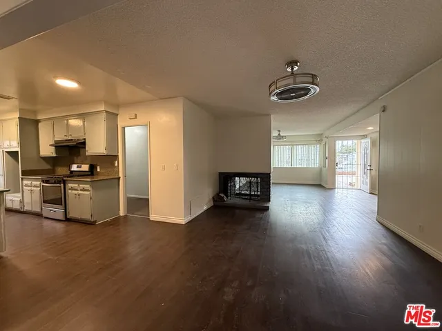 a view of a electric appliances in kitchen and an empty room with wooden floor