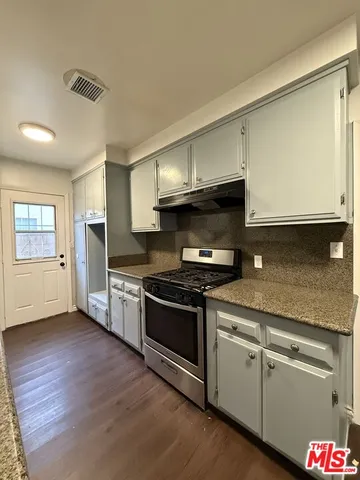 a kitchen with granite countertop a sink cabinets and stainless steel appliances
