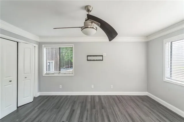 an empty room with wooden floor ceiling fan and windows