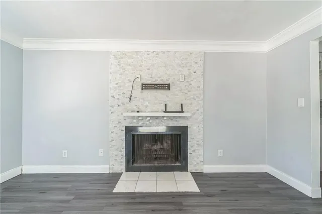 a view of an empty room with wooden floor and a fireplace